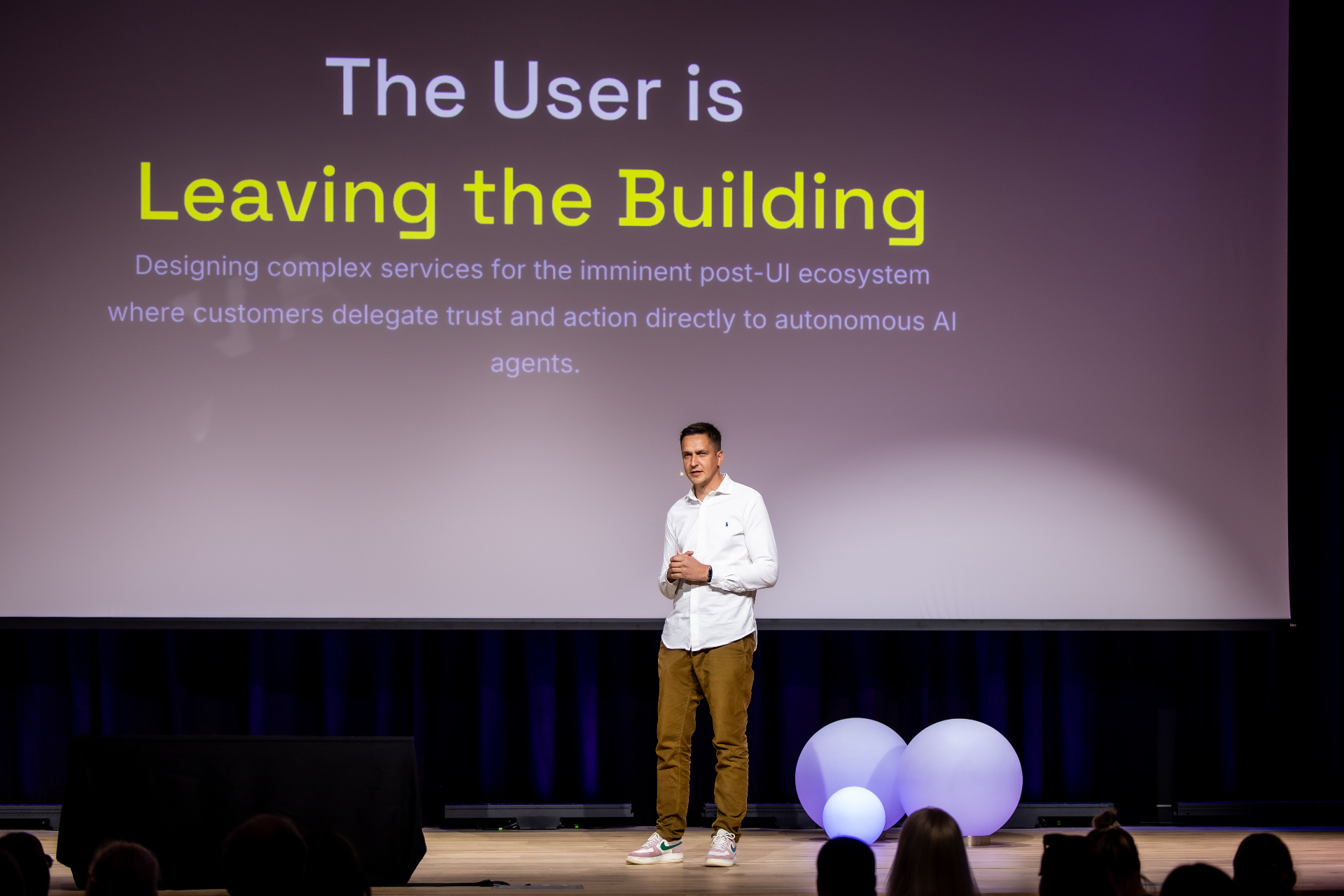 Indrek Reimand speaking on stage at Service Design Day 2026 in front of a large screen reading The User Is Leaving the Building.